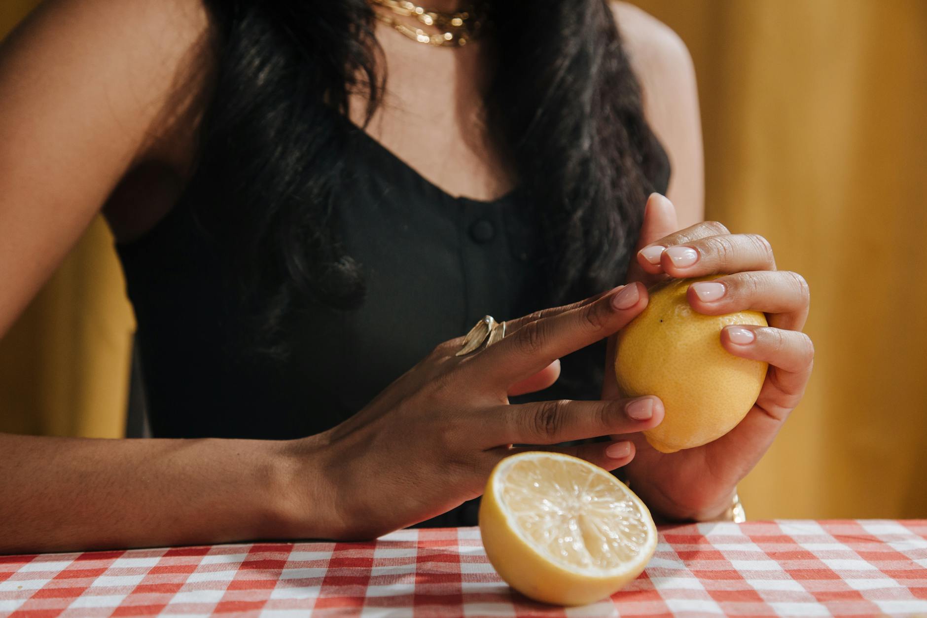 Una donna con i capelli neri tiene un fresco limone al tavolo da pranzo, simbolo di rinascita e vitalità.