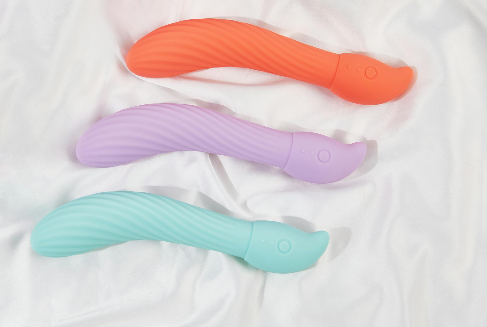 Three colorful lemon vibrators arranged on soft white fabric, displaying smooth silicone texture and ergonomic design.