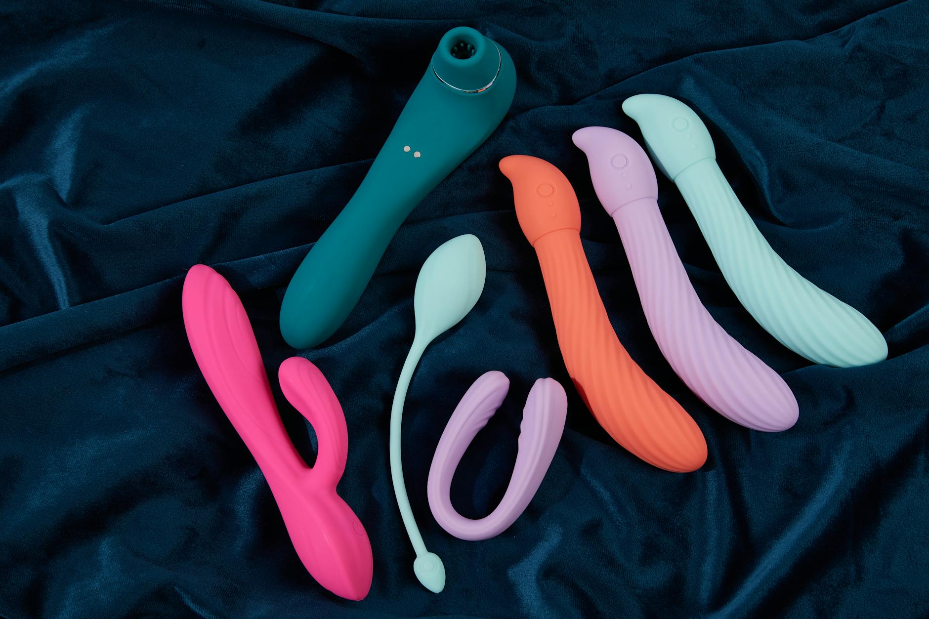 Hand holding a basket of colorful vibrators with fresh flowers, representing shared pleasure and intimacy