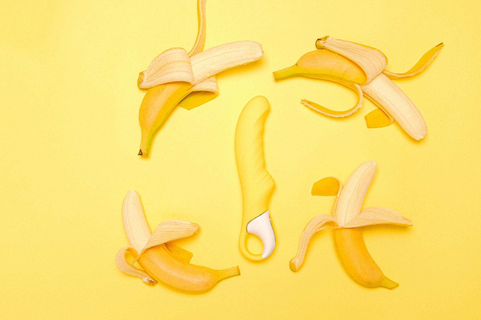 A yellow lemon vibrator surrounded by fresh lemons on a bright yellow background