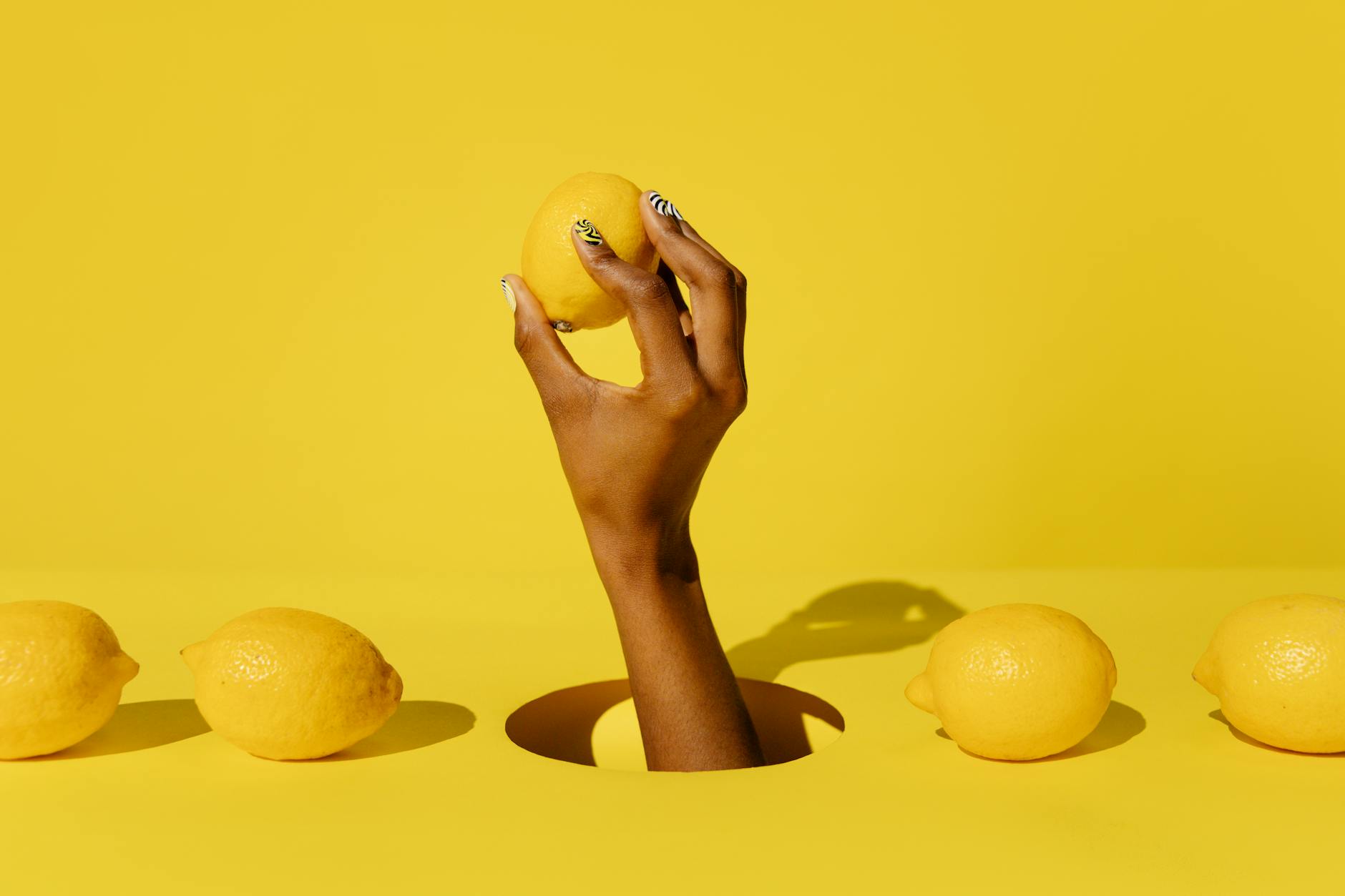 Una mano tiene un limone fresco contro uno sfondo giallo vivido, simboleggiando rinascita e sensazione ritrovata