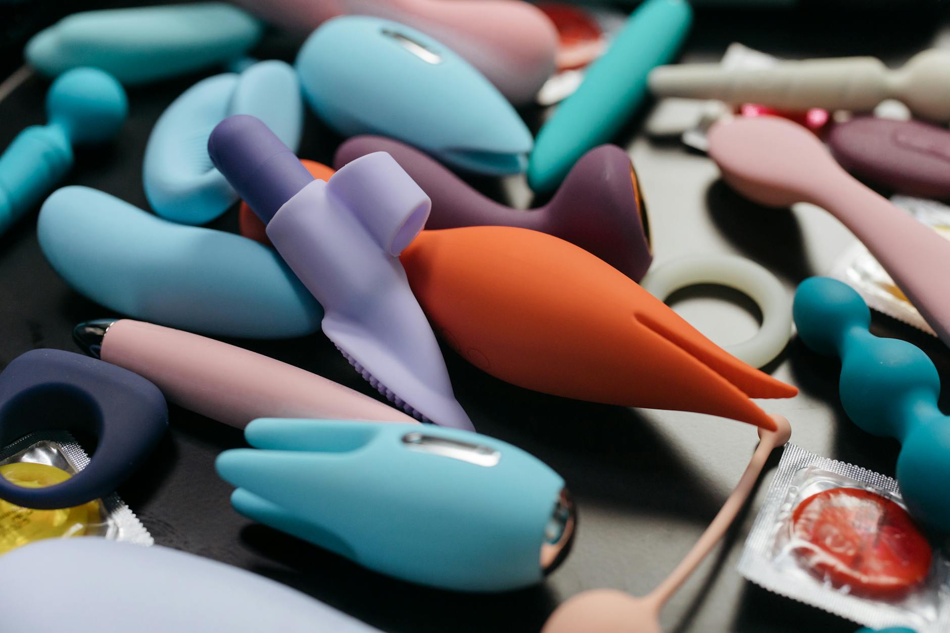 Close-up array of colorful silicone vibrators and adult toys on a neutral background