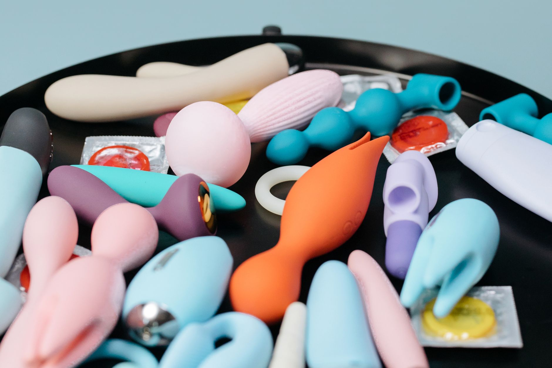A collection of colorful sex toys on a black surface