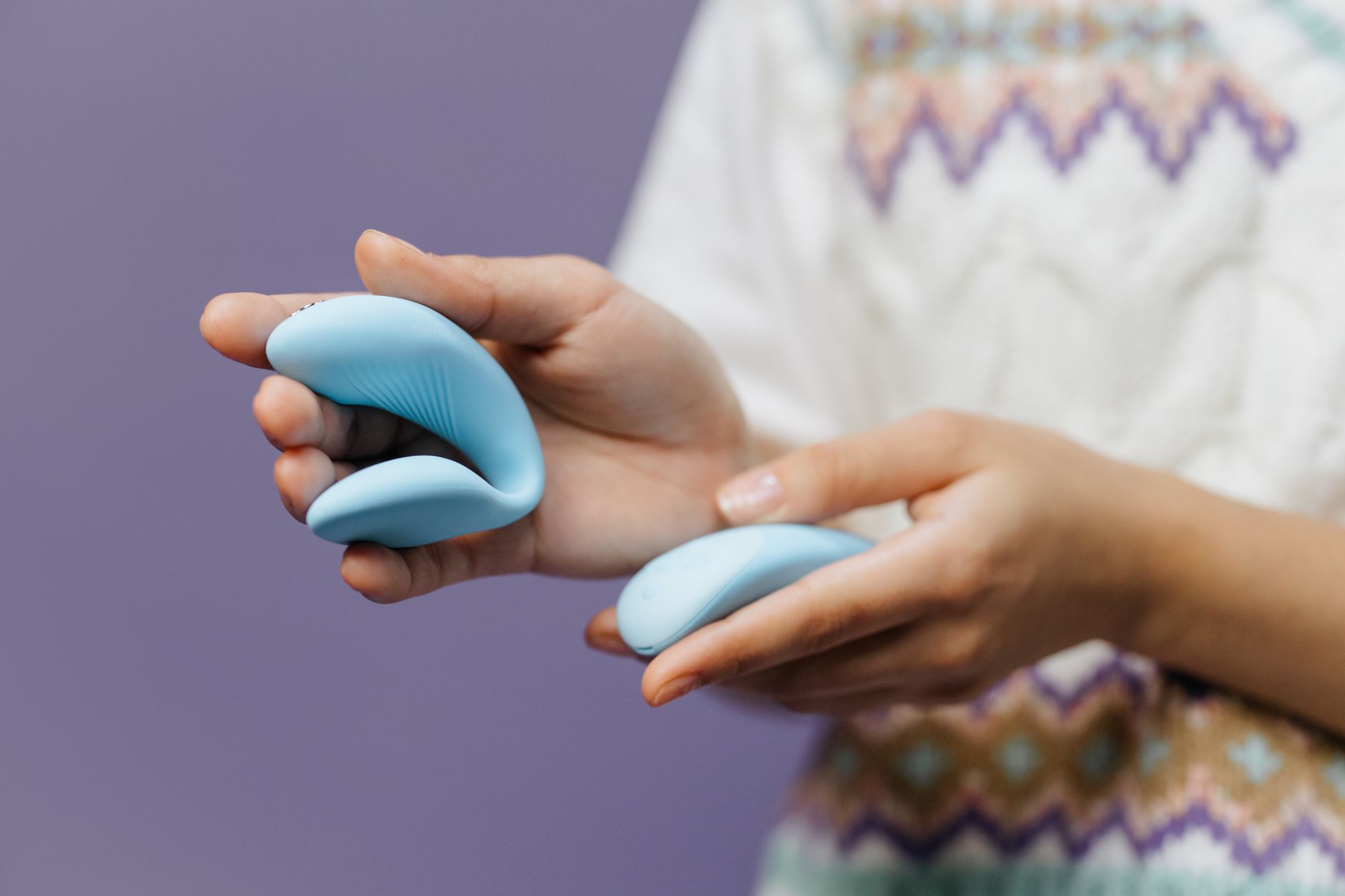 Close-up of hands holding a sleek blue vibrator, representing intimate self-care and solo pleasure rediscovery.