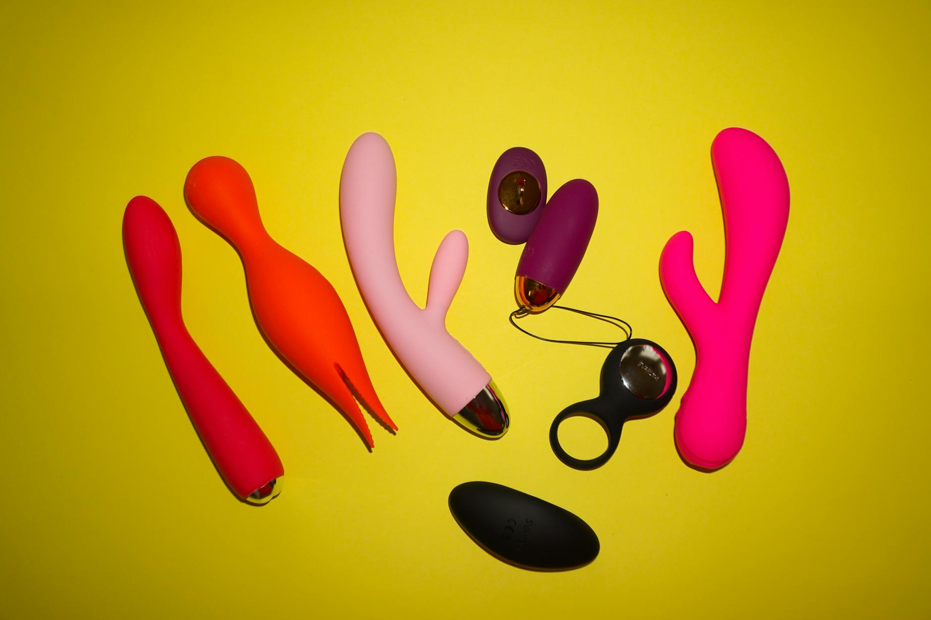 Vibrant collection of colorful silicone clitoral vibrators on a bright yellow background